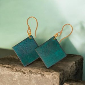 Boucles d'oreilles carrées en cuir teinté vert d'eau, finition lisse, vues de face se chevauchant, suspendues à des boucles dorées, sur pierre