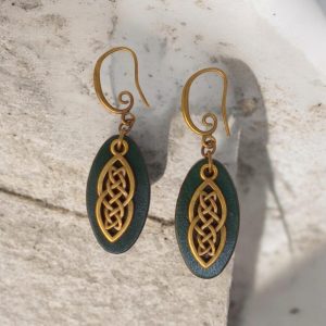 Boucles d'oreilles ovales en cuir teinté vert foncé, finition lisse et pendant celtique, vues de face, suspendues à des boucles couleur bronze sur pierre