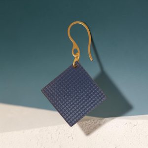 Boucle d'oreille carrée en cuir bleu, texturage quadrillé, vue de face, suspendue à une boucle dorée, fond design