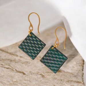 Boucles d'oreilles carrées en cuir teinté vert d'eau, texturage poisson, vues de face, suspendues à des boucles dorées, sur pierre