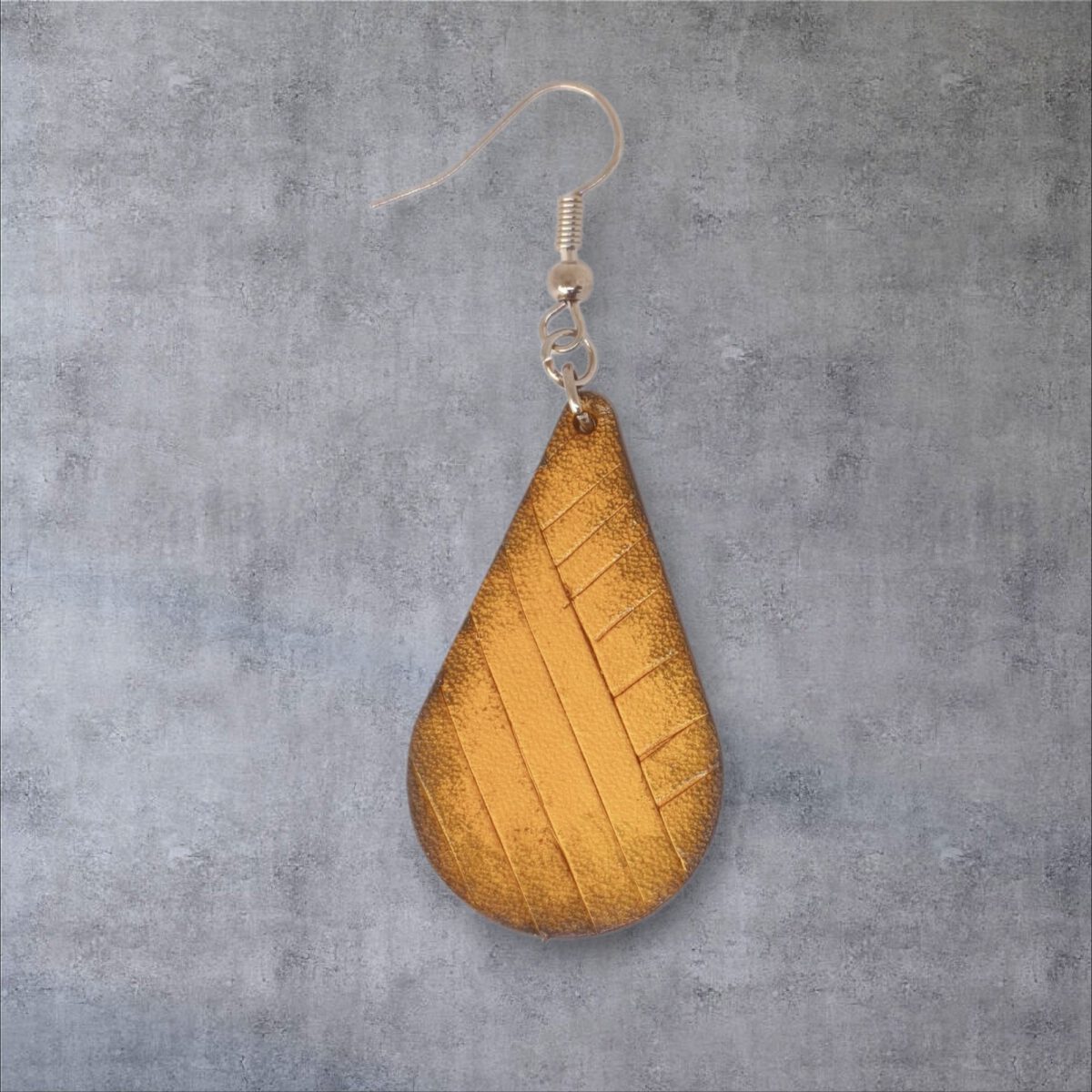 Boucle d'oreille forme goutte d'eau en cuir teinture jaune dégradée, finition griffée, vue de face, suspendue à une boucle argentée, fond gris