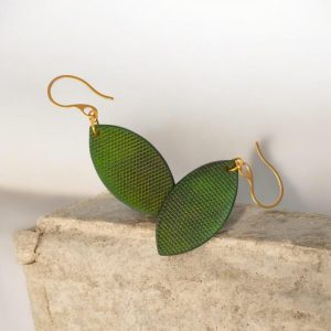 Boucles d'oreilles forme poisson en cuir teinture vert forêt, texturage lime épaisse, vues de face se chevauchant, suspendues à des boucles dorées sur pierre