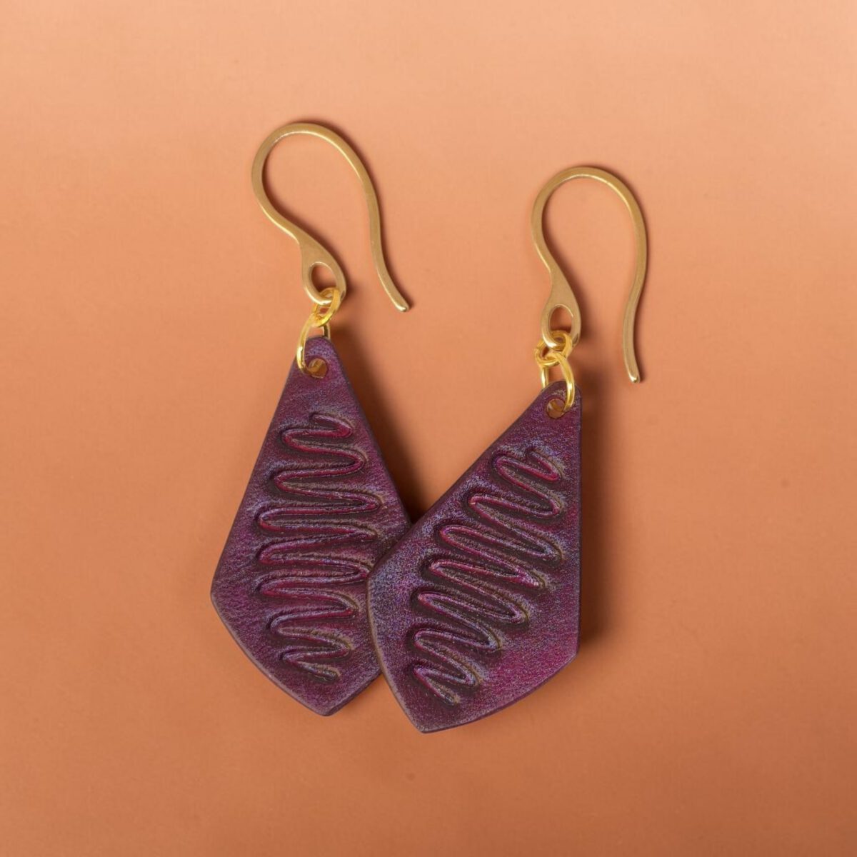 Boucles d'oreilles forme larme en cuir teinture violette, estampage "Lombard Street", vues de face se chevauchant, suspendues à des boucles dorées