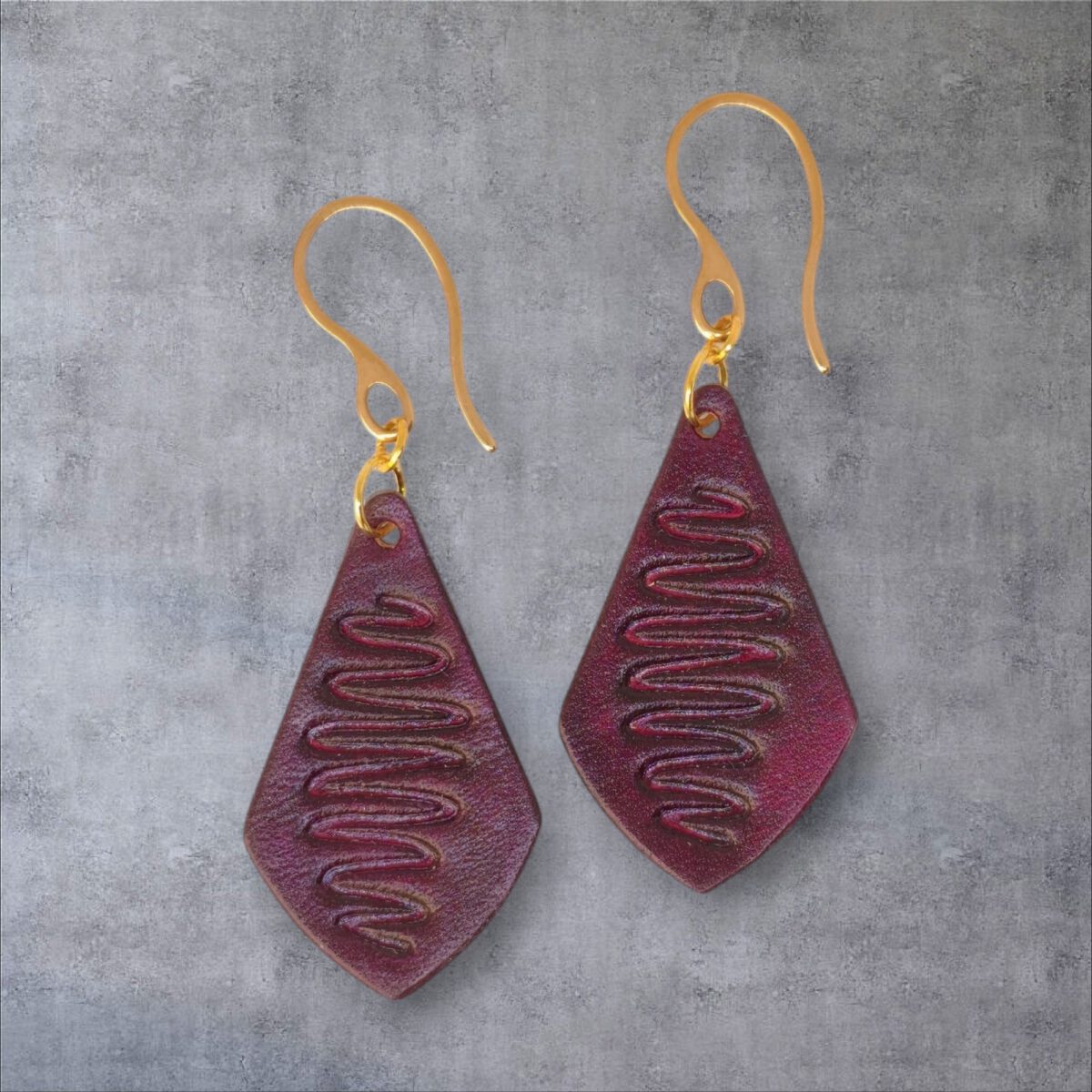 Boucles d'oreilles forme larme en cuir teinture violette, estampage "Lombard Street", vues de face, suspendues à des boucles dorées, fond gris