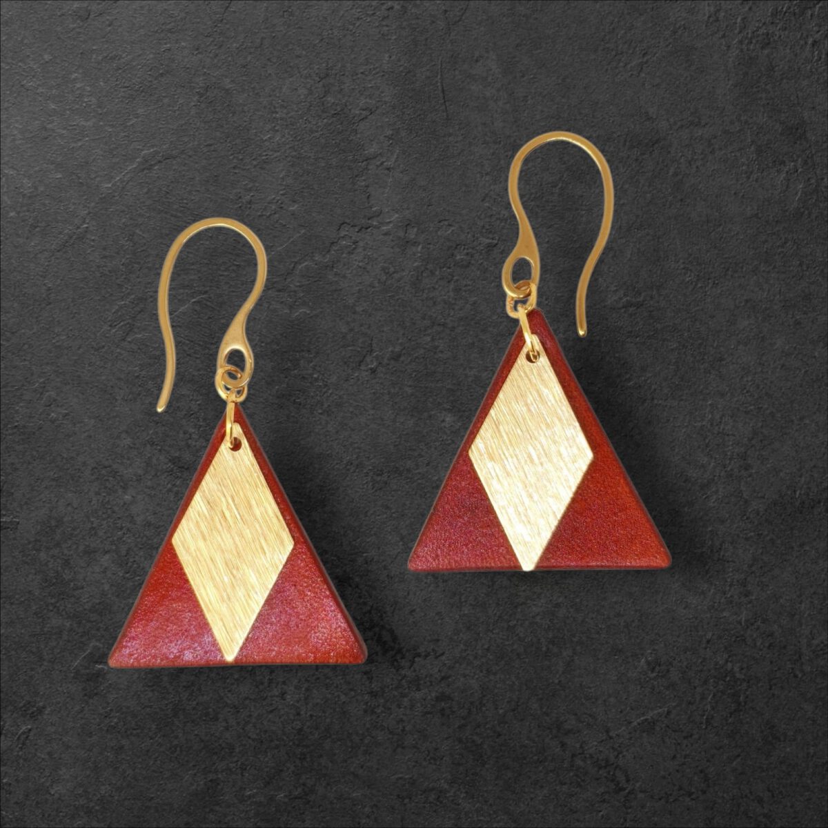 Boucles d'oreilles forme triangulaire en cuir teinture cognac, finition lisse et pendants losange dorés brossés vues de face, suspendues à des boucles dorées sur fond noir