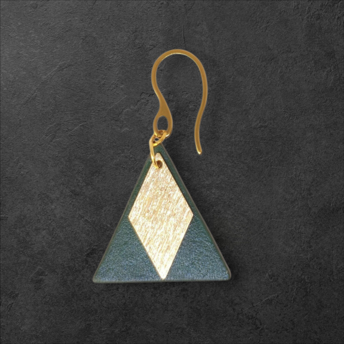 Boucle d'oreille forme triangulaire en cuir teinture vert sombre, finition lisse et pendant losange doré brossé, vue de face, suspendue à une boucle dorée, fond noir