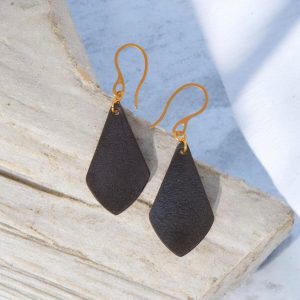 Boucles d'oreilles forme larme en cuir teinture noir charbon, finition lisse, vues de face, suspendues à des boucles dorées sur pierre