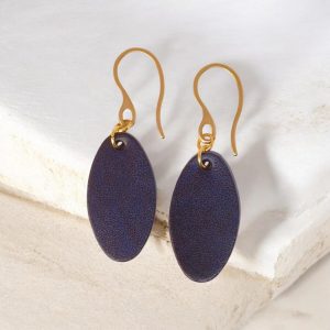 Boucles d'oreilles ovales en cuir sauvage bleu, finition aniline, vues de face, suspendues à des boucles dorées sur pierre