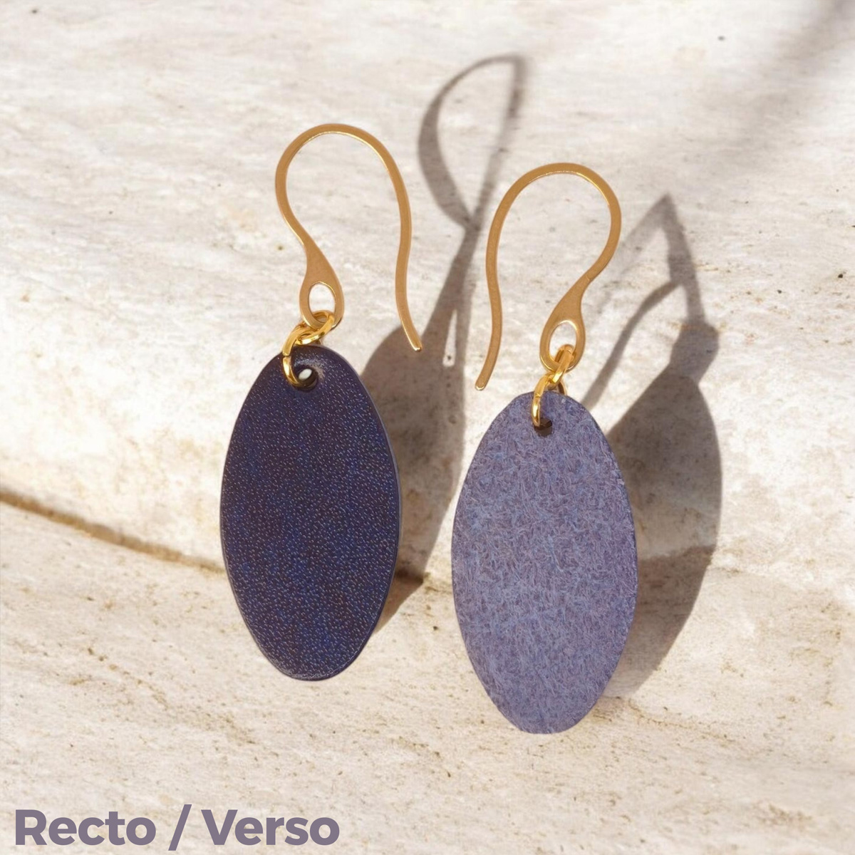 Boucles d'oreilles ovales en cuir sauvage bleu, finition aniline, vues recto - verso, suspendues à des boucles dorées sur pierre
