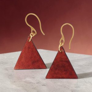 Boucles d'oreilles forme triangulaire en cuir teinture cognac, finition lisse, vues de face, suspendues à des boucles dorées sur béton