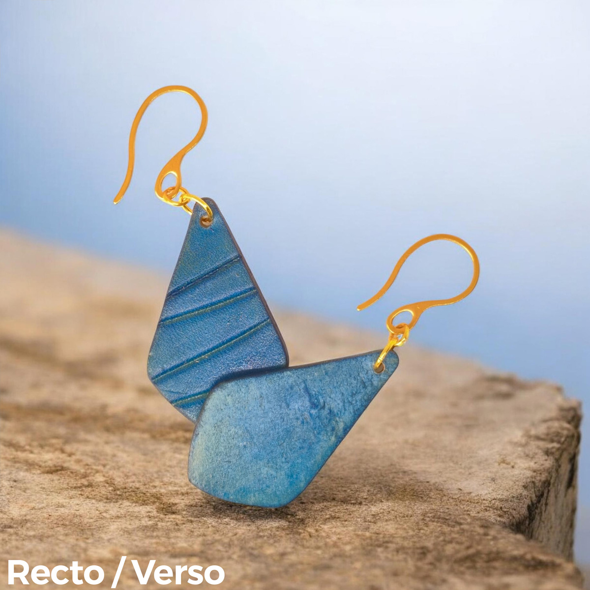 Boucles d'oreilles forme larme en cuir teinté bleu, finition galet, vues recto - verso se chevauchant, suspendues à des boucles dorées
