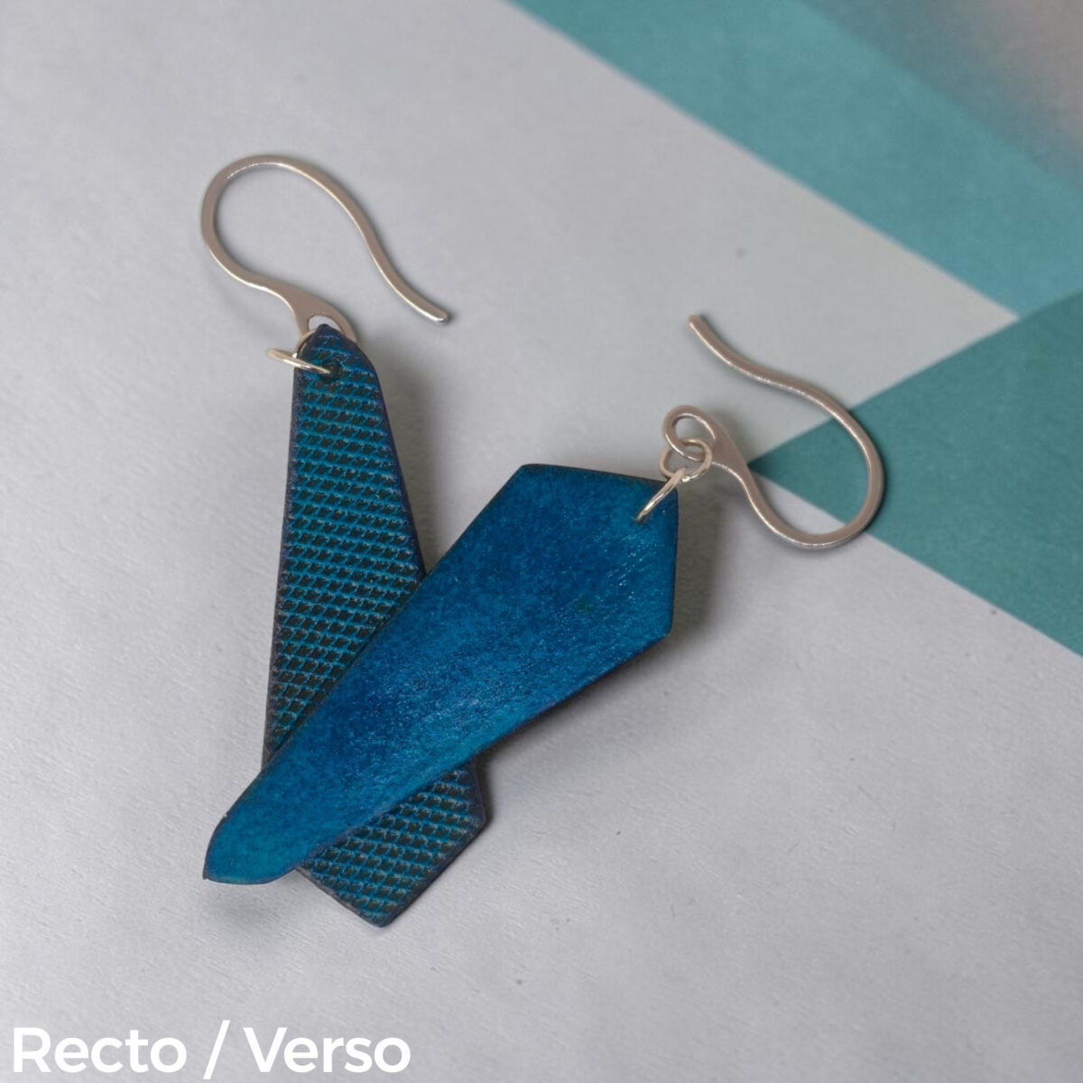 Boucles d'oreilles asymétriques en cuir teinte bleue, vues recto - verso se chevauchant, suspendues à des boucles argentées