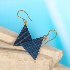 Boucles d'oreilles forme triangulaire en cuir teinture bleue, texturage quadrillage, vues de face se chevauchant, suspendues à des boucles dorées sur pierre
