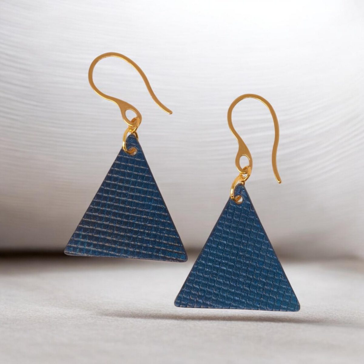 Boucles d'oreilles forme triangulaire en cuir teinture bleue, texturage quadrillage, vues de face, suspendues à des boucles dorées