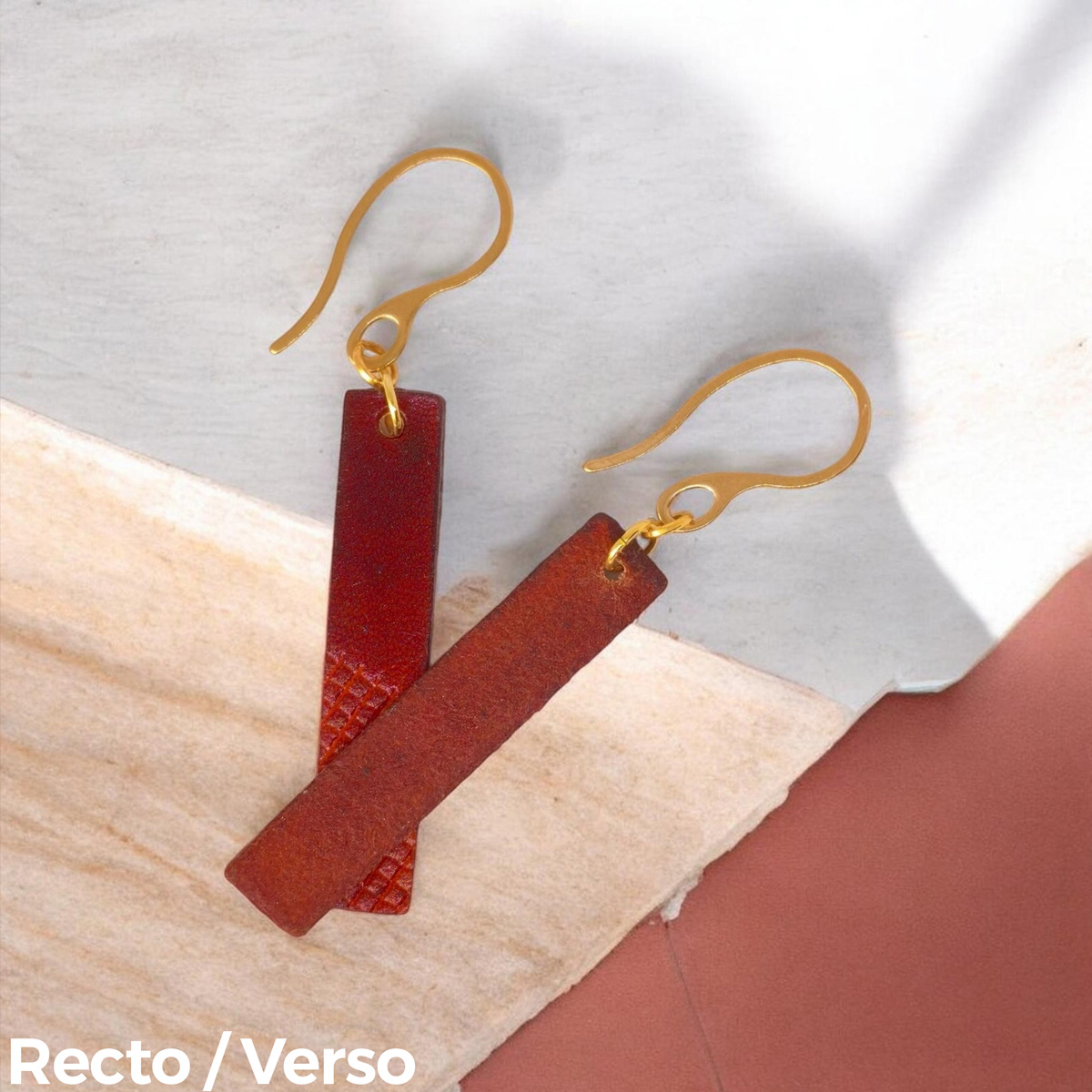 Boucles d'oreilles rectangulaires en cuir teinté cognac et acajou, finition mi-lisse mi-quadrillage , vues recto - verso se chevauchant, suspendues à des boucles dorées sur pierre