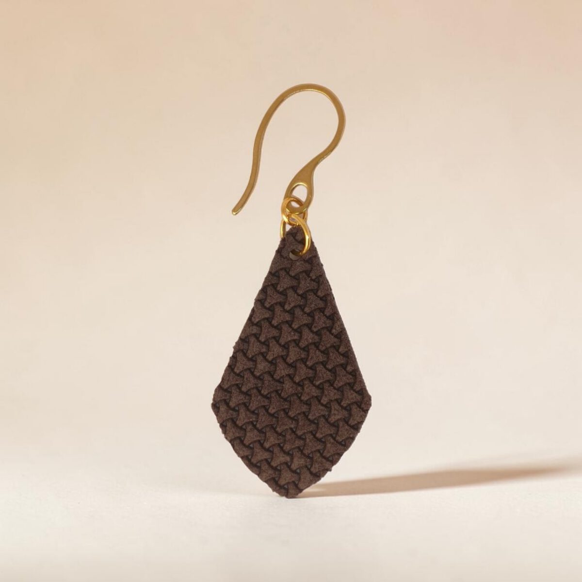 Boucle d'oreille forme larme en cuir texturé, vue de face, suspendues à des boucles dorées sur fond degradé