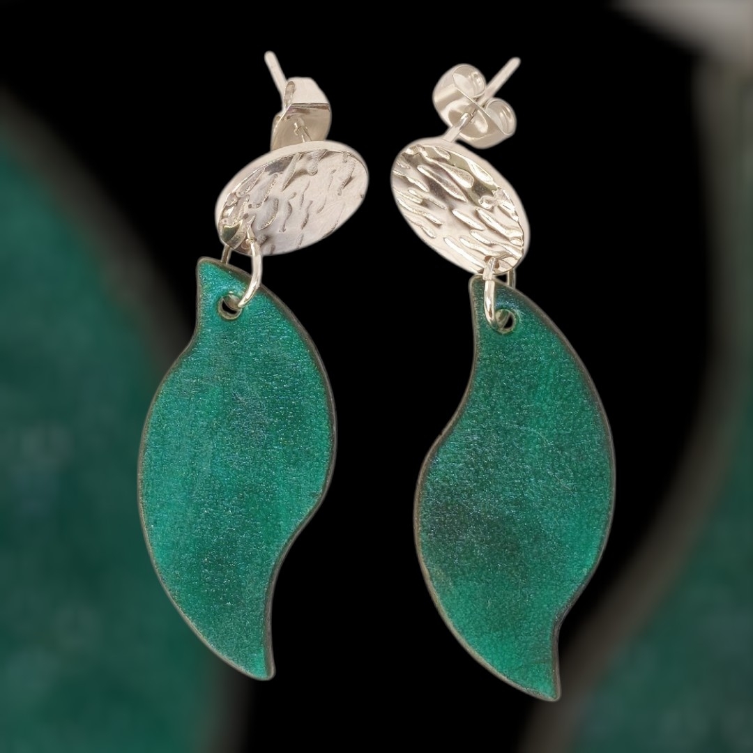 Boucles d'oreilles forme feuille asymétrique en cuir teinté vert d'eau, finition lisse, vues de face, suspendues à des boucles argentées, fond design