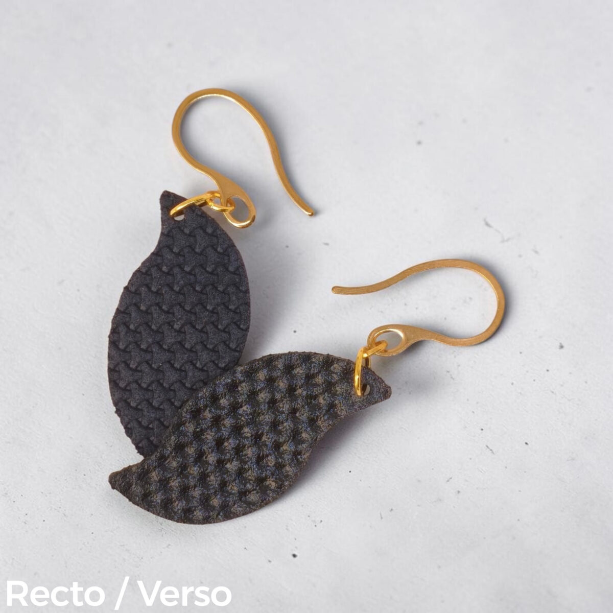 Boucles d'oreilles forme feuille asymétrique en cuir teinté bleu nuit, texturage en tannerie, vues recto - verso se chevauchant, suspendues à des boucles dorées