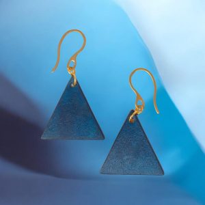 Boucles d'oreilles forme triangulaire en cuir teinture bleue, finition lisse, vues de face, suspendues à des boucles dorées sur fond design