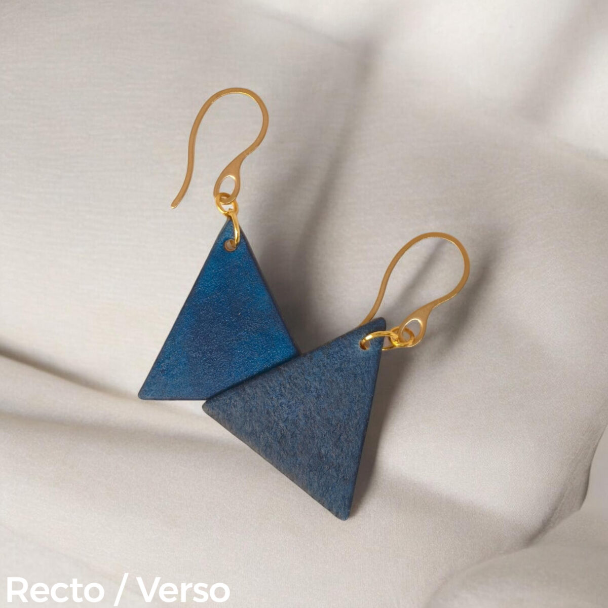 Boucles d'oreilles forme triangulaire en cuir teinture bleue, finition lisse, vues recto - verso se chevauchant, suspendues à des boucles dorées