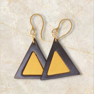 Boucles d'oreilles forme triangulaire double asymétrique en cuir teinture noire et jaune, finition lisse, vues de face se chevauchant, suspendues à des boucles dorées sur marbre