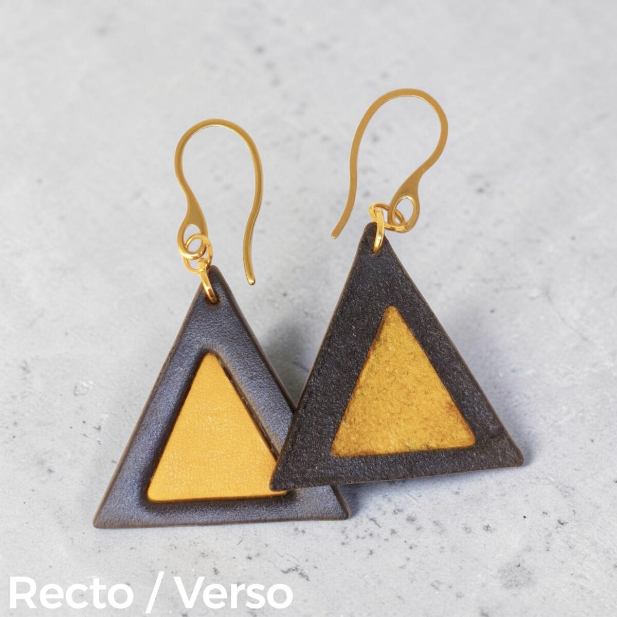 Boucles d'oreilles forme triangulaire double asymétrique en cuir teinture noire et jaune, finition lisse, vues recto - verso se chevauchant, suspendues à des boucles dorées