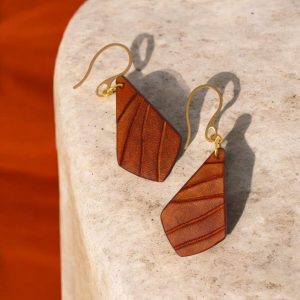 Boucles d'oreilles en cuir teinté cognac, vues de face posées, suspendues à des crochets dorés