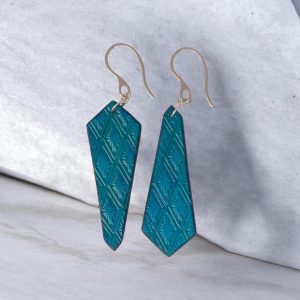 Boucles d'oreilles cravates asymétriques en cuir teinté bleu, estampage au matoir, vues de face, suspendues à des boucles argentées sur une pierre