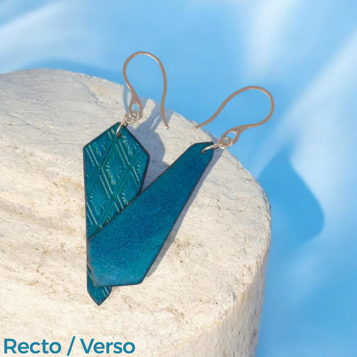 Boucles d'oreilles cravates asymétriques en cuir teinté bleu, estampage au matoir, vues recto - verso se chevauchant, suspendues à des boucles argentées sur pierre
