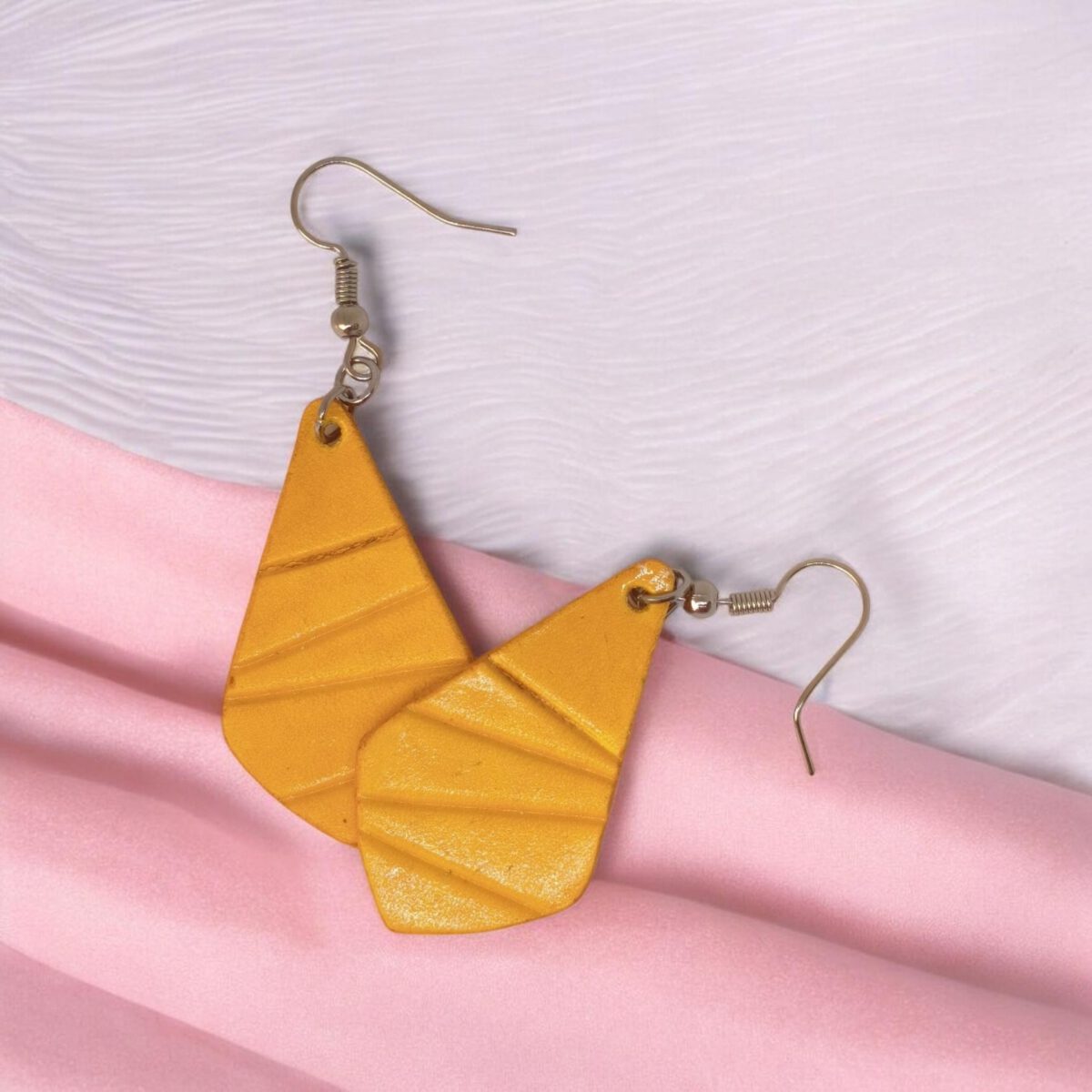 Boucles d'oreilles forme larme en cuir teinture jaune, finition galet, vues de face se chevauchant, suspendues à des boucles argentées