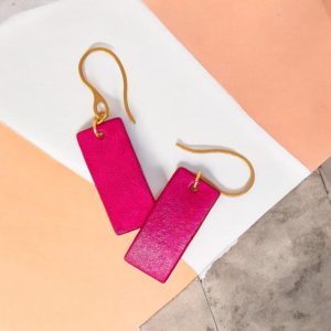 Boucles d'oreilles en cuir teintées en fuschia très girly et vives, vues de face se chevauchant, suspendues à des crochets dorés