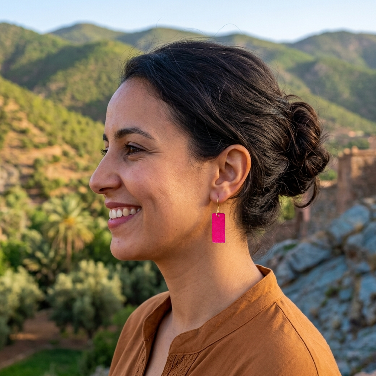 Boucles d'oreilles en cuir teintées en fuschia très girly et vives, vues de face, suspendues à des crochets dorés sur un mannequin virtuel