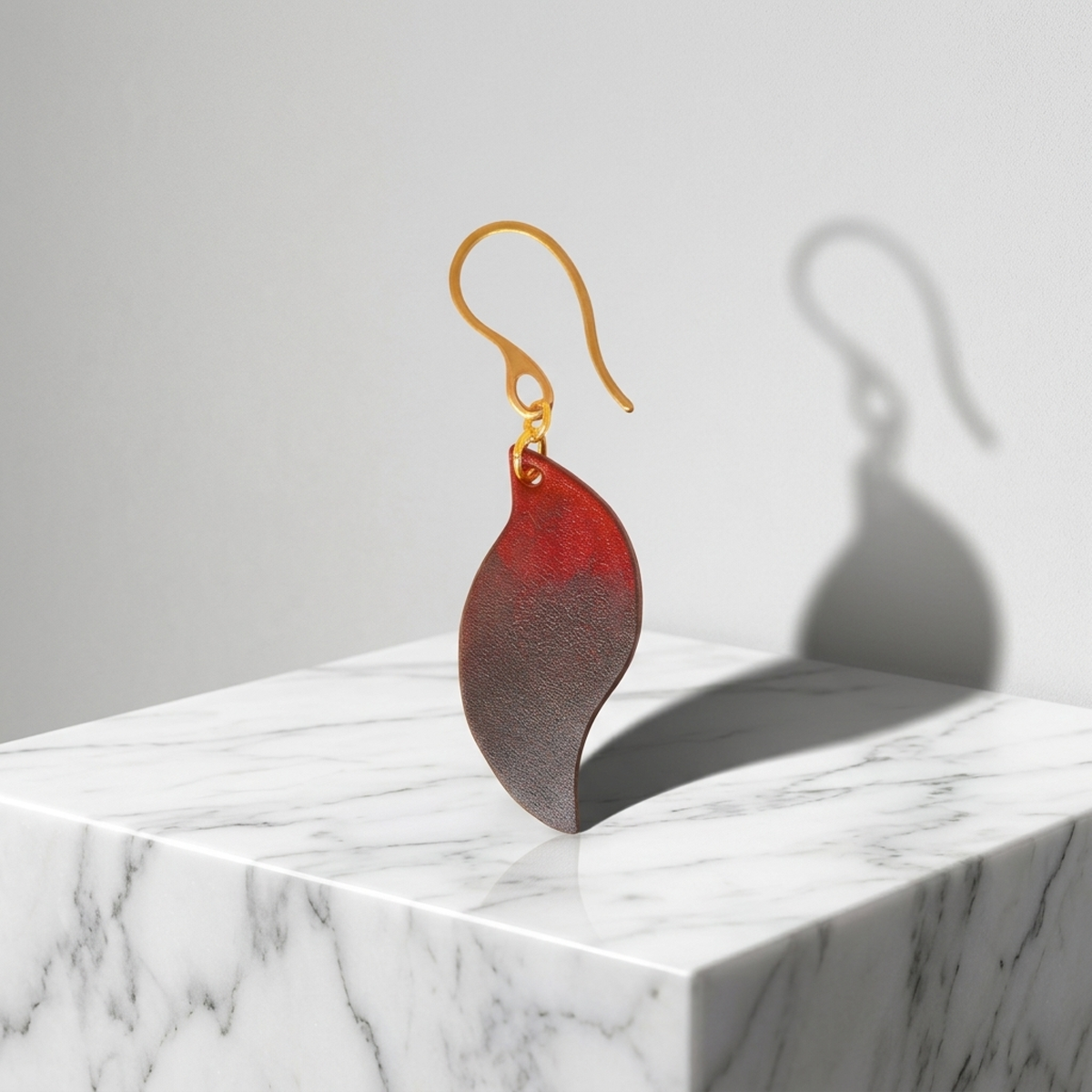 Boucle d'oreille en cuir teintée en noir et rouge, vue de face solo, suspendue à un crochet doré
