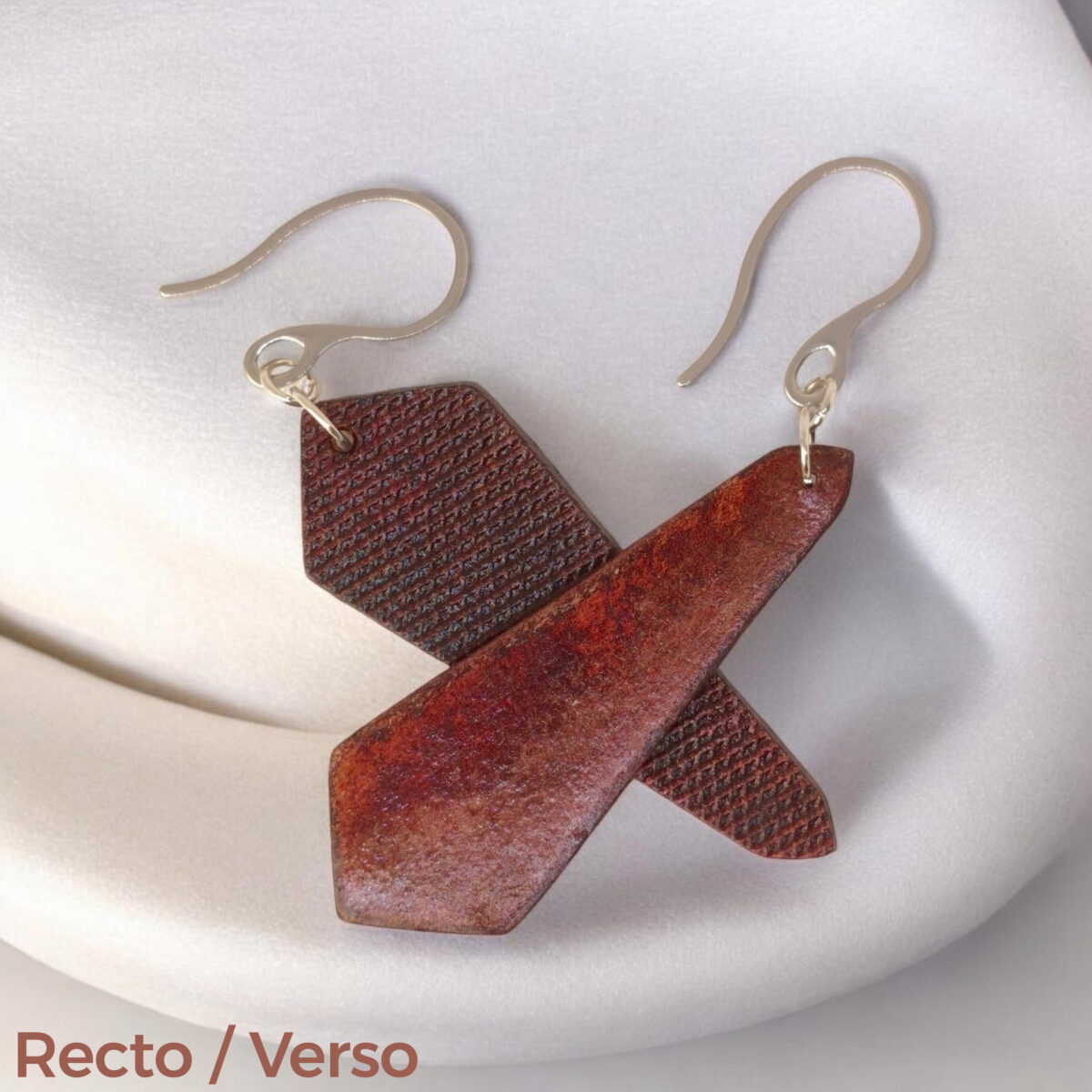 Boucles d'oreilles asymétriques en cuir teinture acajou, vues recto - verso se chevauchant, suspendues à des crochets argentés sur fond design