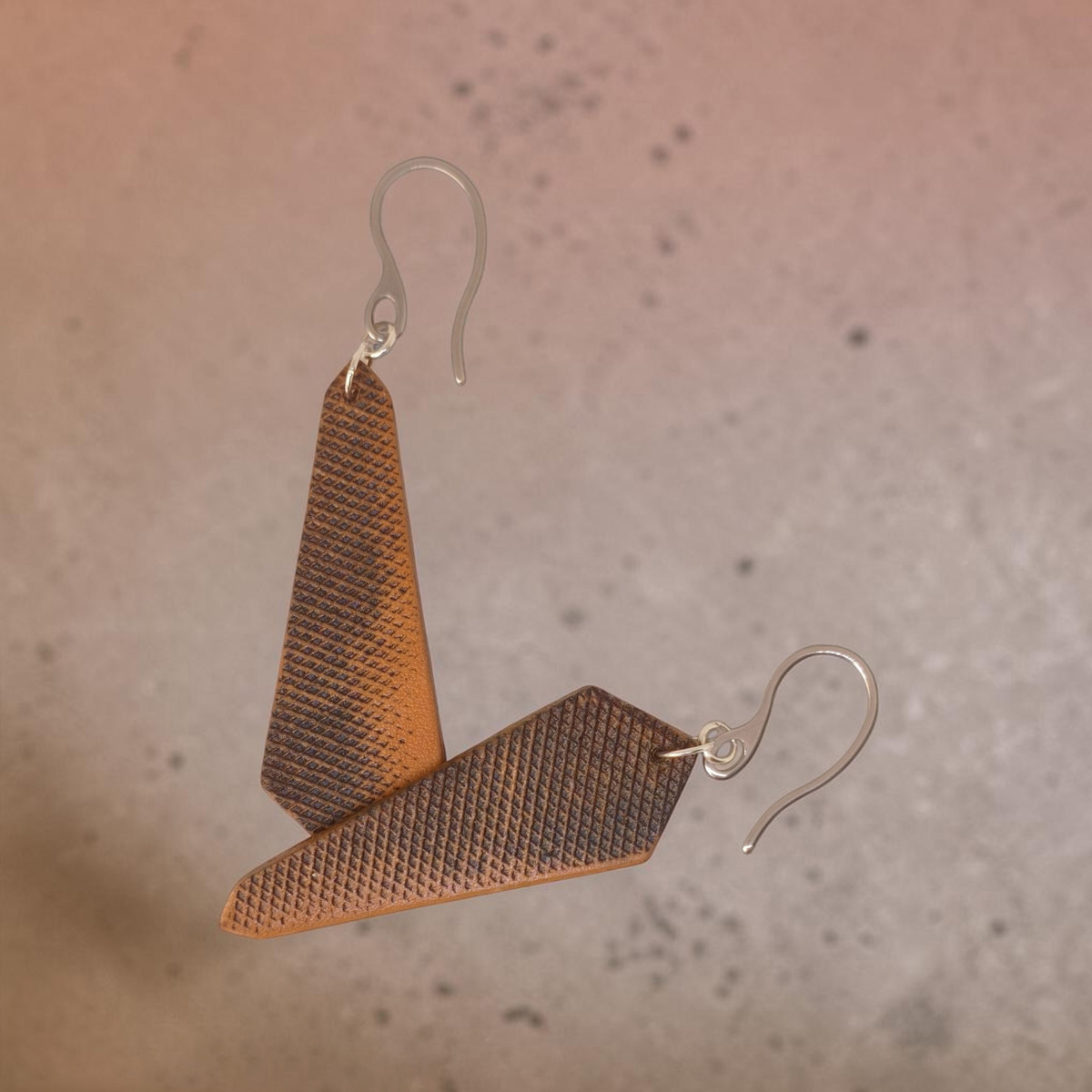 Boucles d'oreilles asymétriques en cuir huilées teinte naturelle, vues de face se chevauchant, suspendues à des crochets argentés
